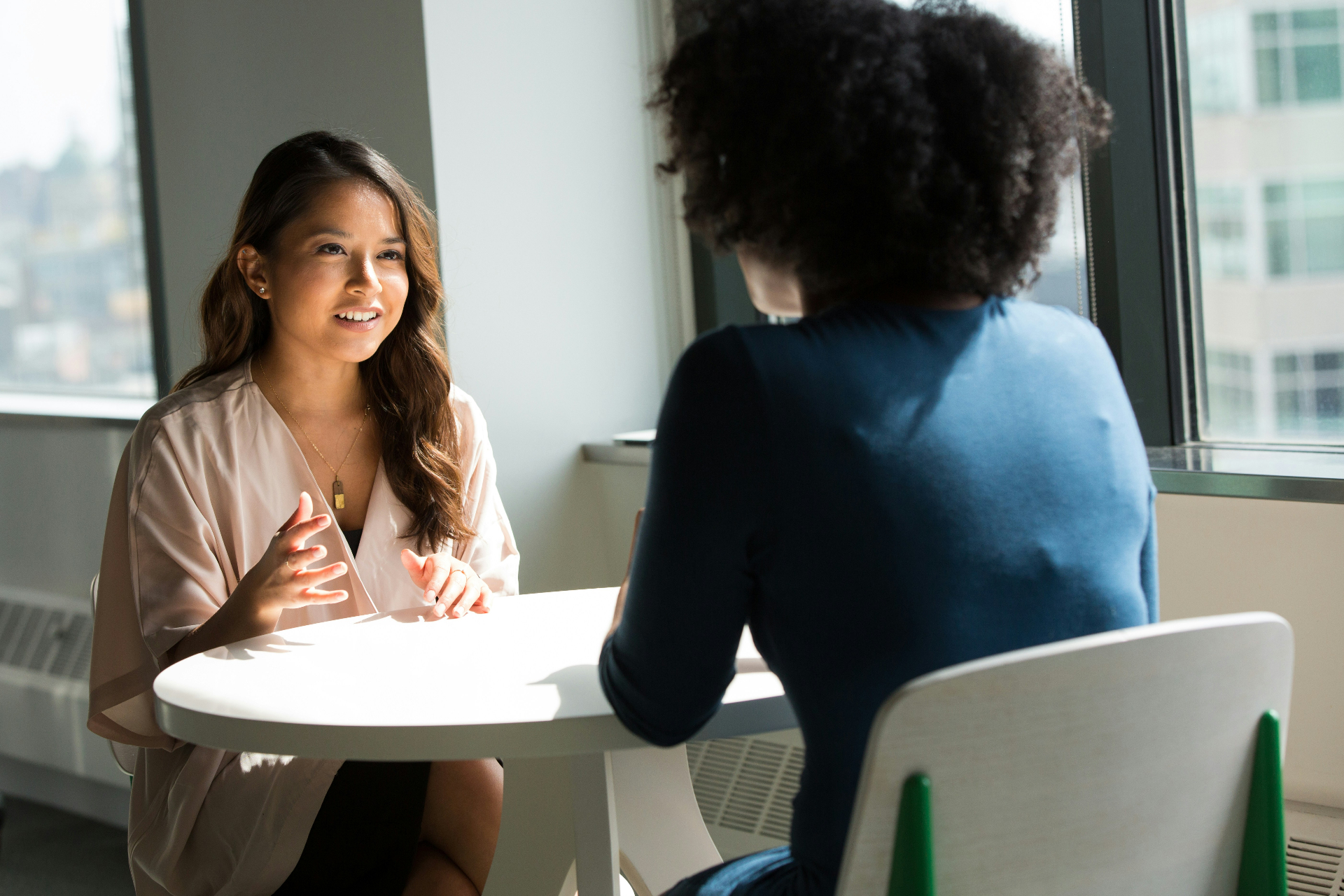 Two colleagues having a candid interview conversation by a sunlit window